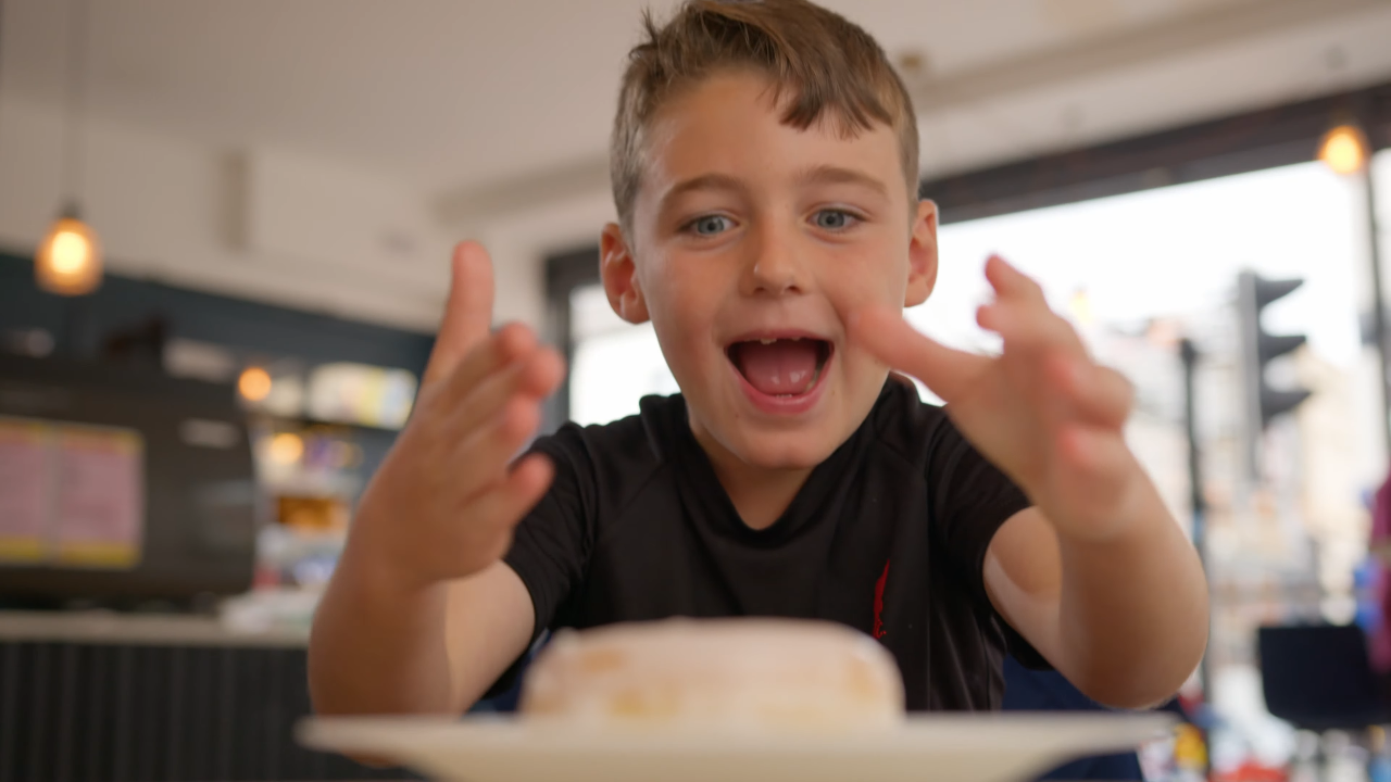Young boy smiles as he is about to eat a delicious doughnut creation from Liverpool-based Holey Dough.
